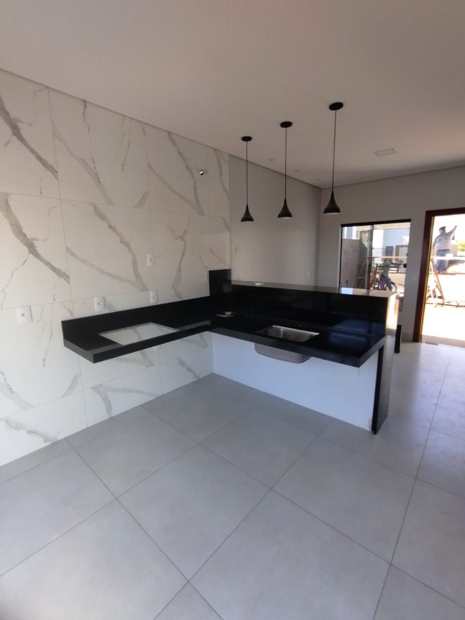 Cozinha com bancada em granito preto e revestimento marmorizado