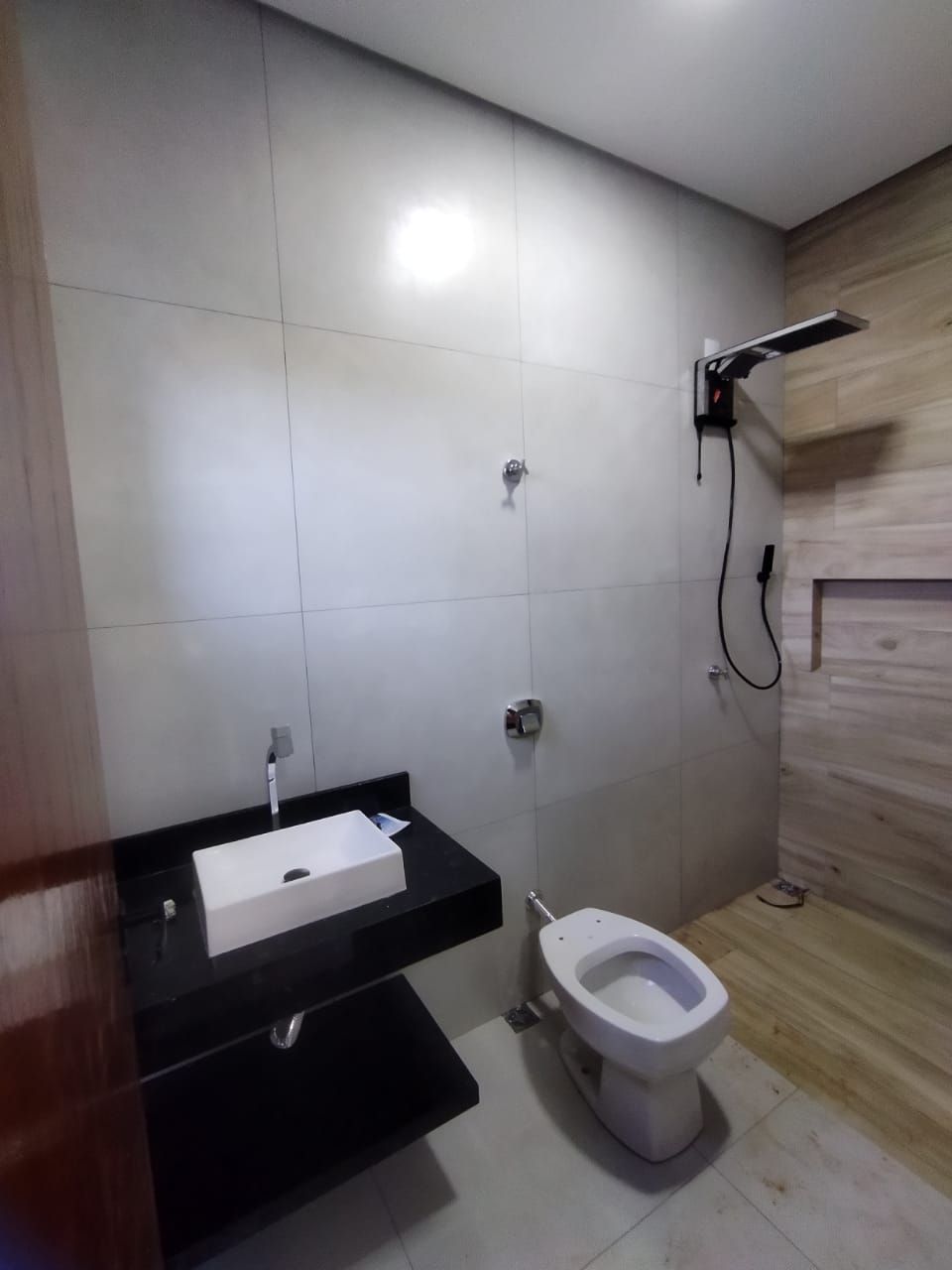 Banheiro com piso amadeirado e bancada preta